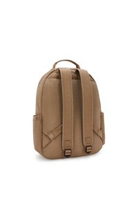 Mochila de tela color beige con dos correas acolchadas para los hombros, un asa en la parte superior, bolsillos laterales y una forma redondeada. Superficie texturizada, acentos mínimos.