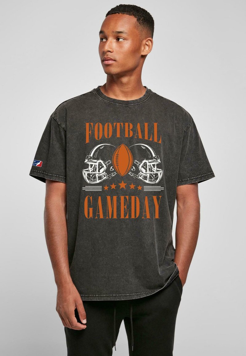 Musta graafinen t-paita, jossa oranssia tekstiä "FOOTBALL GAMEDAY" ja kuvia jalkapallokypäristä. Lyhyet hihat, rento istuvuus, pehmeä tekstuuri.