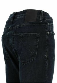 Jean en denim bleu foncé vu de dos, avec des poches cousues, des passants pour ceinture et un patch de marque noir à la taille.