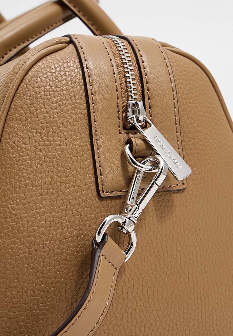 Sac à main en cuir texturé beige avec une fermeture éclair argentée, un clip en métal et une sangle d'épaule amovible.