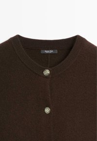 Col de cardigan en maille marron foncé avec deux boutons argentés embossés et étiquette "Massimo Dutti" à l'intérieur de l'encolure.