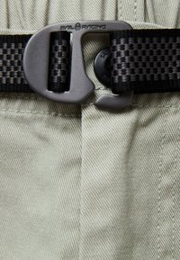 Beige cargobroek met een textuurstof, een zwarte geweven riem en een duurzame grijze gesp met het 'Sail Racing' merk.