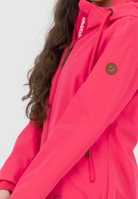 Helle pinke wasserdichte Jacke mit Kapuze, ausgestattet mit elastischen Kordeln, Reißverschlusstaschen und einem runden Logopatches am Ärmel.