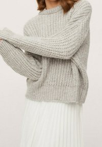 Vaaleanharmaa neulepaita, jossa on kuvioitu pinta, pitkät hihat ja rento istuvuus, yhdistetty valkoiseen laskostettuun hameeseen.