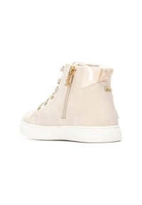 Zapatilla alta de ante beige con detalles dorados, cremallera lateral y suela de goma blanca. Detalle texturizado en el talón con diseño de logo.