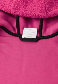 Ružová mikina s fleece podšívkou a hladkým, rebrovaným vnútrom. Čierny lem obklopuje otvor; vo vnútri je všitý štítok pre personalizáciu.