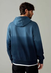 Heren hoodie in een gradient van blauwtinten, gemaakt van zachte stof, heeft een trekkoordkap en ribgebreide manchetten en onderkant.
