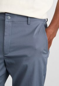 Gray fabric trousers with a smooth texture, featuring a button closure, side pockets, and a tailored fit. No visible patterns or accents.