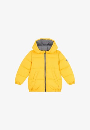 Dzeltena pūkaina jaka ar kapuci, pelēka svītrota oderējuma, priekšējais rāvējslēdzis un divas sānu kabatas. Iezīmē elastīgas aproces un noapaļots apakšmalu.