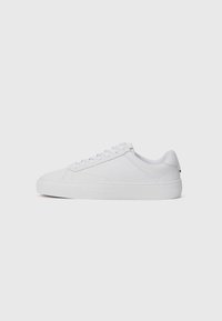 White low-top sneakers made of smooth leather, featuring a rounded toe, flat laces, and a textured rubber sole. Minimalist design with no visible branding.
