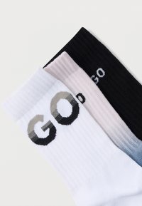 Kolm paari meessokke: valged, roosad ja mustad. Igal paaril on sooniline tekstuur ja sõna "GO" erinevates värvides ja stiilides.