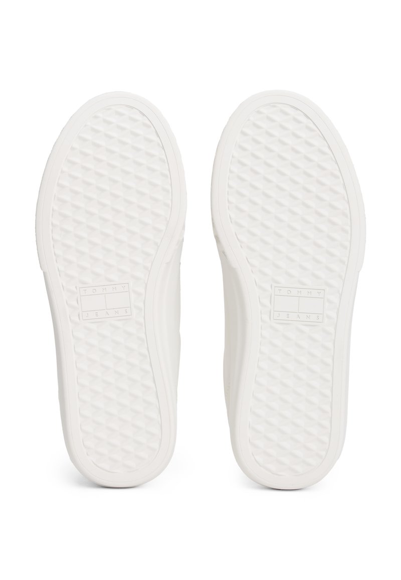 Suole di sneaker bianche con un pattern a diamante testurizzato, forma piatta e dettaglio del logo impressa. Materiale liscio senza accenti visibili.