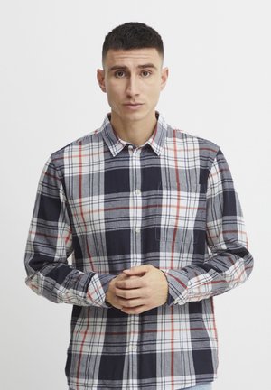 Camisa de botones con patrón de cuadros, en colores azul marino, rojo y blanco. Manga larga, cuello y bolsillo en el pecho con textura de tela suave.