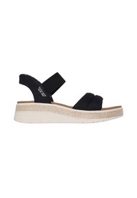 Sandales compensées noires avec des brides en tissu texturé, un bandeau élastique et une semelle intermédiaire de couleur claire, ressemblant à du jute tissé. La semelle comporte des rainures antidérapantes.