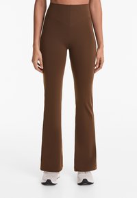 Braune, ausgestellte Yogahosen mit hohem Bund, aus dehnbarem Material; glatte Textur und keine sichtbaren Muster oder Verzierungen.
