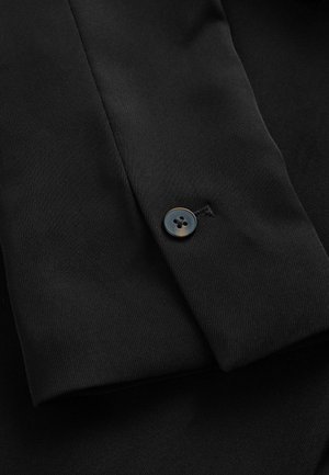 Black fabric featuring a smooth texture and a button on the cuff, displaying a subtle sheen against a dark background.