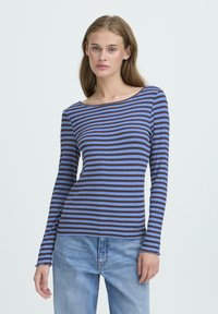 Langærmet stribet top i blå og brun med en bådudskæring, blød tekstur og let slidte manchetter. Kombineret med lyse denim jeans.