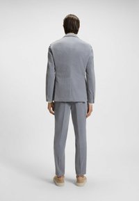 Completo grigio chiaro a due pezzi con strisce verticali, vestibilità sartoriale, tessuto testurizzato e rever a scollo. Include pantaloni abbinati e scarpe beidge.