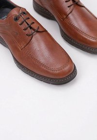 Brown leather shoes with a textured finish, round toe, lace-up design, and contrasting stitching on a rubber sole.