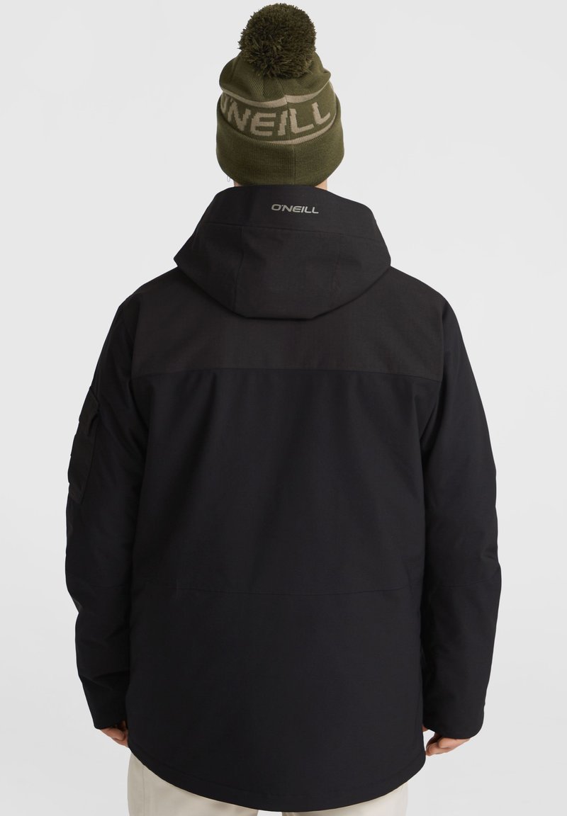 Czarna kurtka z kapturem i długimi rękawami, z teksturowaną górną częścią i logo na plecach. W zestawie z oliwkowym czapką z pomponem.
