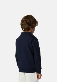 Felpa blu navy con scollo rotondo, polsini e orlo a costine. Realizzata in tessuto morbido, presenta un piccolo dettaglio testuale sulla manica.