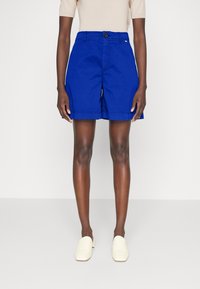 Niebieskie bawełniane szorty o klasycznym kroju, z dopasowaną talią i bocznymi kieszeniami. Projekt zawiera zapięcie na guzik oraz staranne detale szewne.