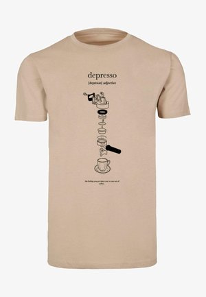 Beżowy t-shirt z czarnym wzorem graficznym przedstawiającym ekspres do kawy i filiżankę, z towarzyszącym tekstem definiującym "depresso".