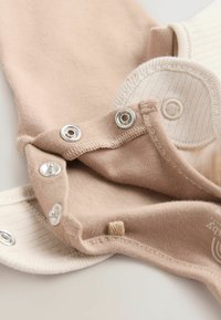 Bodysuit pour bébé en coton dans des tons beige doux et crème, avec des boutons-pression et des accents côtelés pour un habillage facile et un confort optimal.