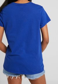 Blå bomulls t-shirt med en avslappnad passform, korta ärmar och rund hals. Tyget verkar slätt med en enhetlig färg och inga synliga mönster.