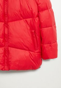 Veste matelassée rouge vif avec fermeture éclair frontale et poche latérale, montrée de la taille jusqu'au haut du bras sur fond blanc.