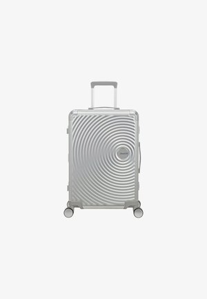 Valise rigide argentée avec texture en spirale, poignée rétractable et quatre roues pour une mobilité facile.