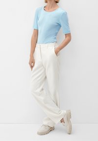 Ljusblå kortärmad topp matchad med vita plisserade byxor och beige plattformsskor, med fokus på deras släta texturer och rena linjer.