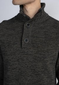 Maglione lavorato a maglia di colore grigio scuro con un motivo testurizzato, dotato di un colletto alto e due bottoni neri sullo scollo.