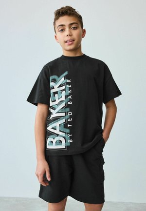 Čierne tričko s výraznou vertikálnou grafikou v bielej a tyrkysovej farbe, na ktorej je nápis "BAKER by TED BAKER." Kombinované s čiernymi šortkami. Voľné, krátke rukávy.