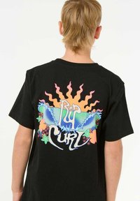 T-shirt noir avec un imprimé graphique coloré au dos, représentant des rayons de soleil, des vagues et des éléments floraux, avec le texte "Rip Curl".