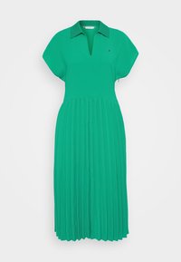 Vihreä pleatattu mekko, jossa on kaulus ja V-pääntie. Valmistettu sileästä kankaasta, lyhyet hihat ja aaltoileva hame.