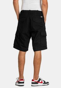 Pantalones cortos de carga negros con dos bolsillos laterales, dos bolsillos traseros y un ajuste relajado. Hechos de tejido ligero, aptos para uso casual.