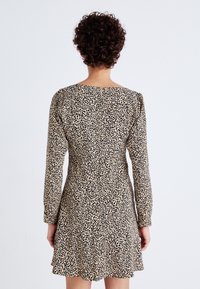 Une robe à imprimé léopard avec des manches longues, un col rond et un ourlet évasé. Le tissu est léger avec une texture lisse.