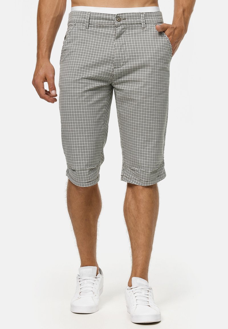 Checkered shorts in black and white, made from lightweight fabric, featuring side and back pockets, rolled hems, and a front button closure.