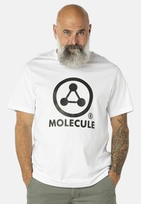 Valkoinen puuvillapaita, jossa on musta molekyylilogo ja tekstinä "MOLEKYYLI" alla. Lyhyet hihat ja rento istuvuus.