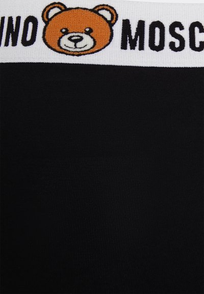 Melnas audums ar baltu elastīgu jostu, kas rotāta ar karikatūras lāča seju un melnu "MOSCHINO" uzrakstu. Gluda tekstūra.