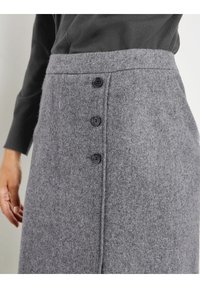 Gonna in lana grigia con una finitura texturizzata, dotata di cinque bottoni neri sulla parte anteriore e una vita alta. Design casual, lunghezza fino al ginocchio.