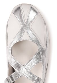Chaussure Mary Jane blanche et argentée avec des brides métalliques en forme de X sur le dessus et un bout arrondi.