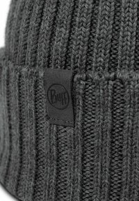Gray knitted beanie featuring a ribbed texture and a black leather patch with the "Buff" logo. Close-up focus on material and details.