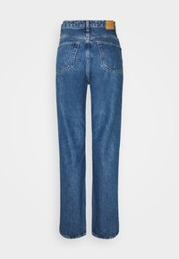 Jeans de mezclilla azul con un diseño de pierna recta, bolsillos traseros y una parche de cuero marrón en la cinturilla. Textura suave y ajuste clásico.