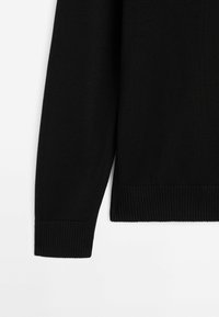 Black knitted sweater sleeve featuring ribbed cuffs and texture. Simple design with no visible patterns or hardware accents.