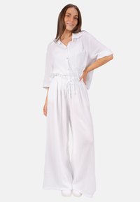 Weißes, leichtes, strukturiertes Baumwoll-Outfit mit einem lässigen, locker sitzenden Button-up-Hemd mit Tasche und elastischen Kordelzug-Hosen.