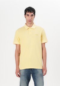 Gul polo skjorte laget av bomull med klassisk krage, to knapper og en subtil "BOSS"-logo brodert på venstre bryst.
