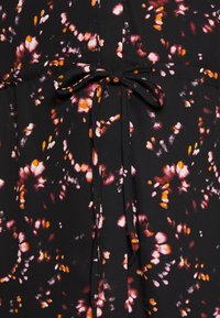 Svart tyg med ett livligt abstrakt mönster i rosa, orange och vitt. Har en knytning i midjan. Slät textur.