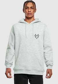 Svetlošedá mikina s kapucňou vyroben�á z mäkkej látky, s šnúrkou na kapucni, prednou vreckom a čiernym logom na hrudi. Uvoľnený strih.